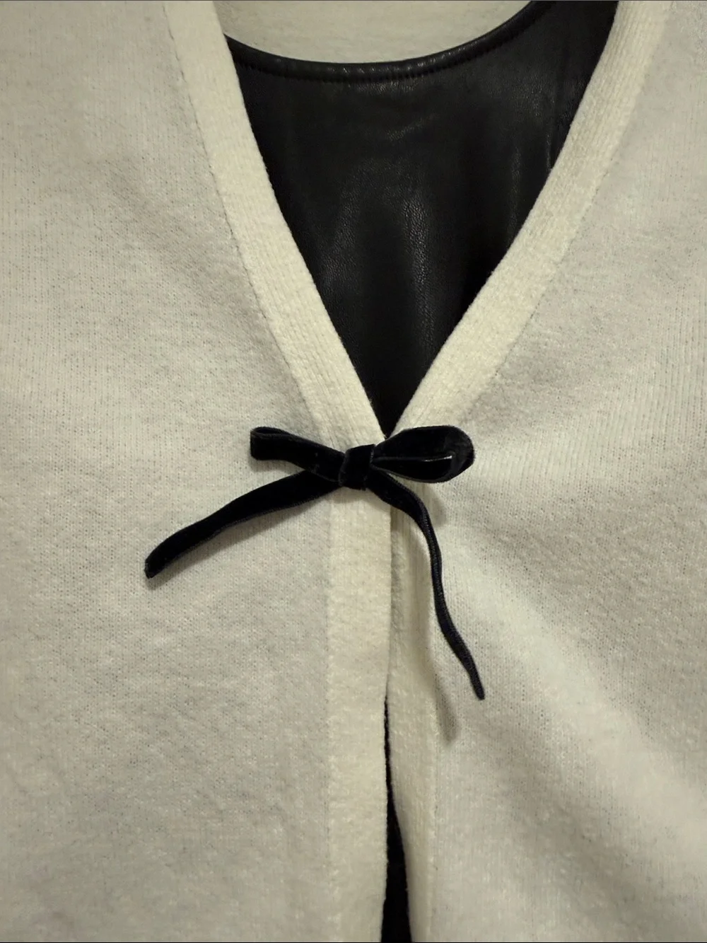 White Cropped Cardigan with Black Bow Over Black Faux Leather Dress
